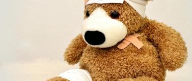 An injured teddy bear that has patched with bandages